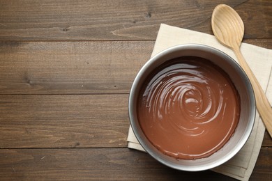 Photo of Chocolate dough in bowl and spoon on wooden table, top view. Space for text