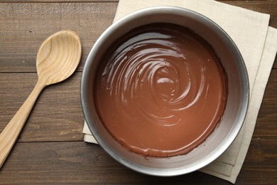 Photo of Chocolate dough in bowl and spoon on wooden table, top view