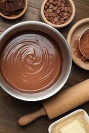 Photo of Chocolate dough in bowl and ingredients on wooden table, flat lay