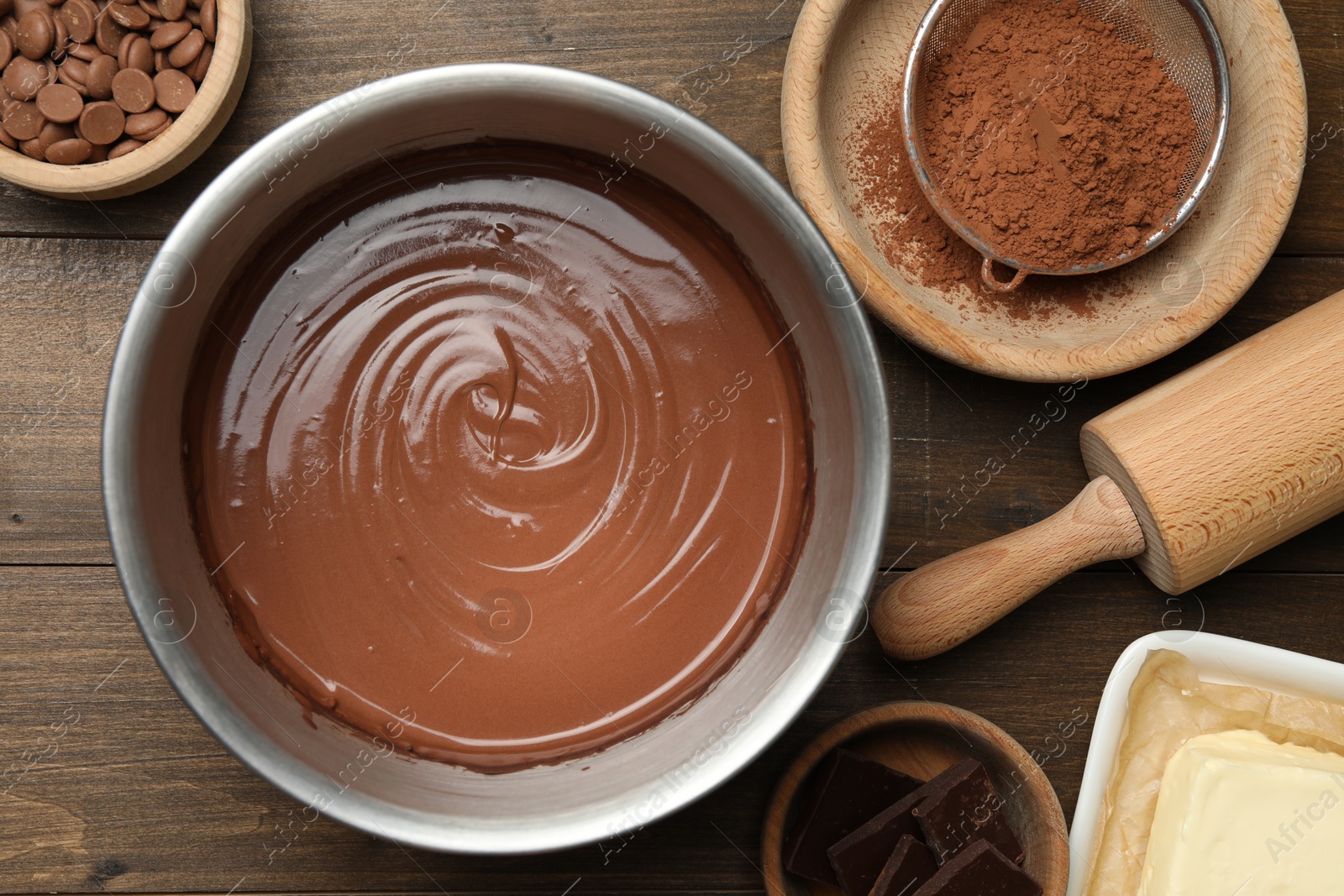 Photo of Chocolate dough in bowl and ingredients on wooden table, flat lay