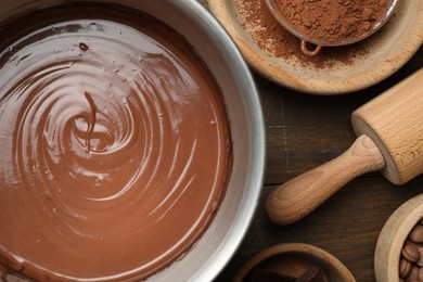 Photo of Chocolate dough in bowl and ingredients on wooden table, flat lay