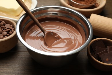 Photo of Chocolate dough in bowl and ingredients on wooden table, closeup