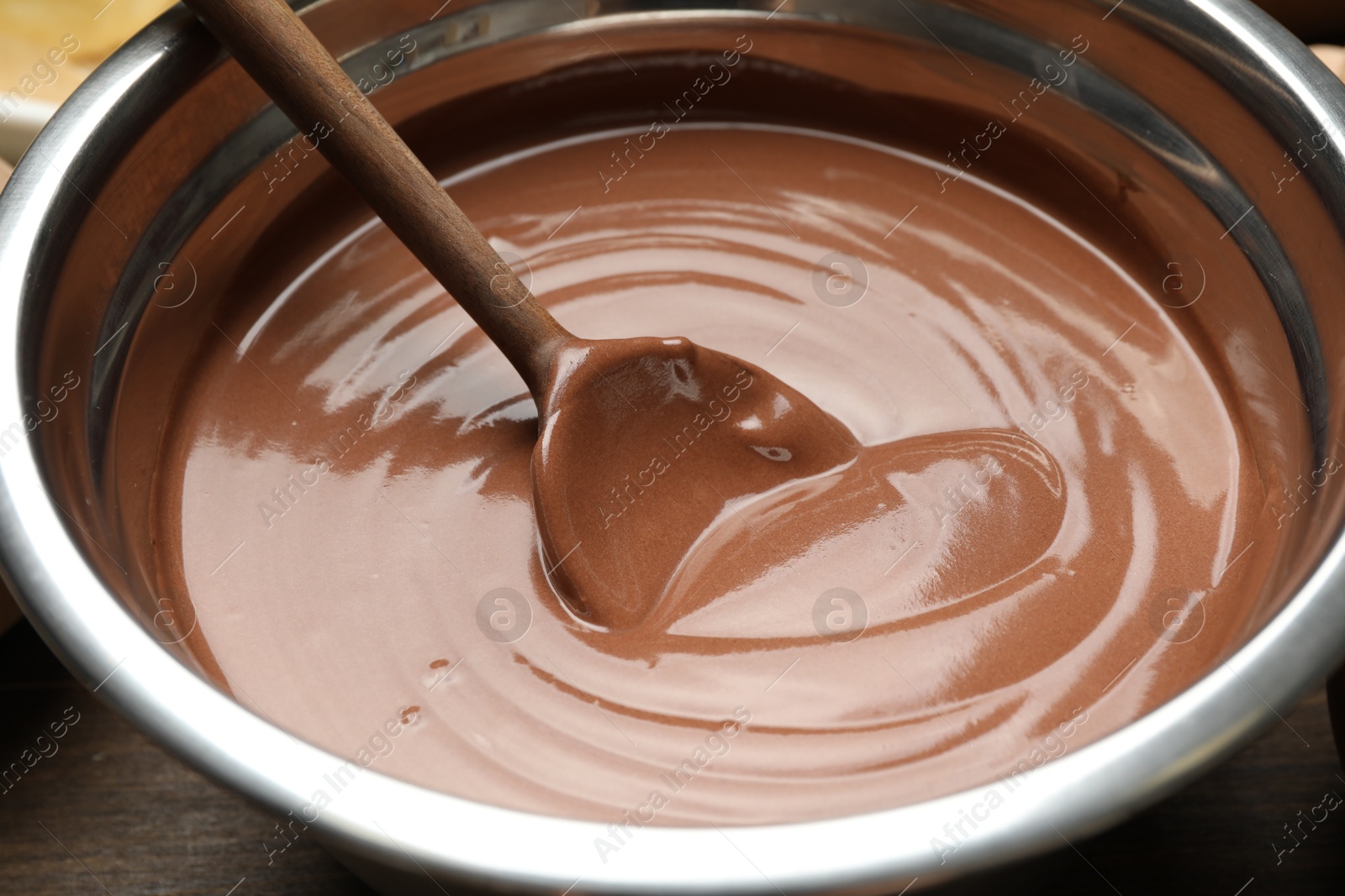 Photo of Chocolate dough and spoon in bowl on table, closeup