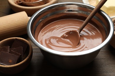 Photo of Chocolate dough in bowl and ingredients on wooden table, closeup