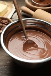 Chocolate dough in bowl and ingredients on wooden table, closeup