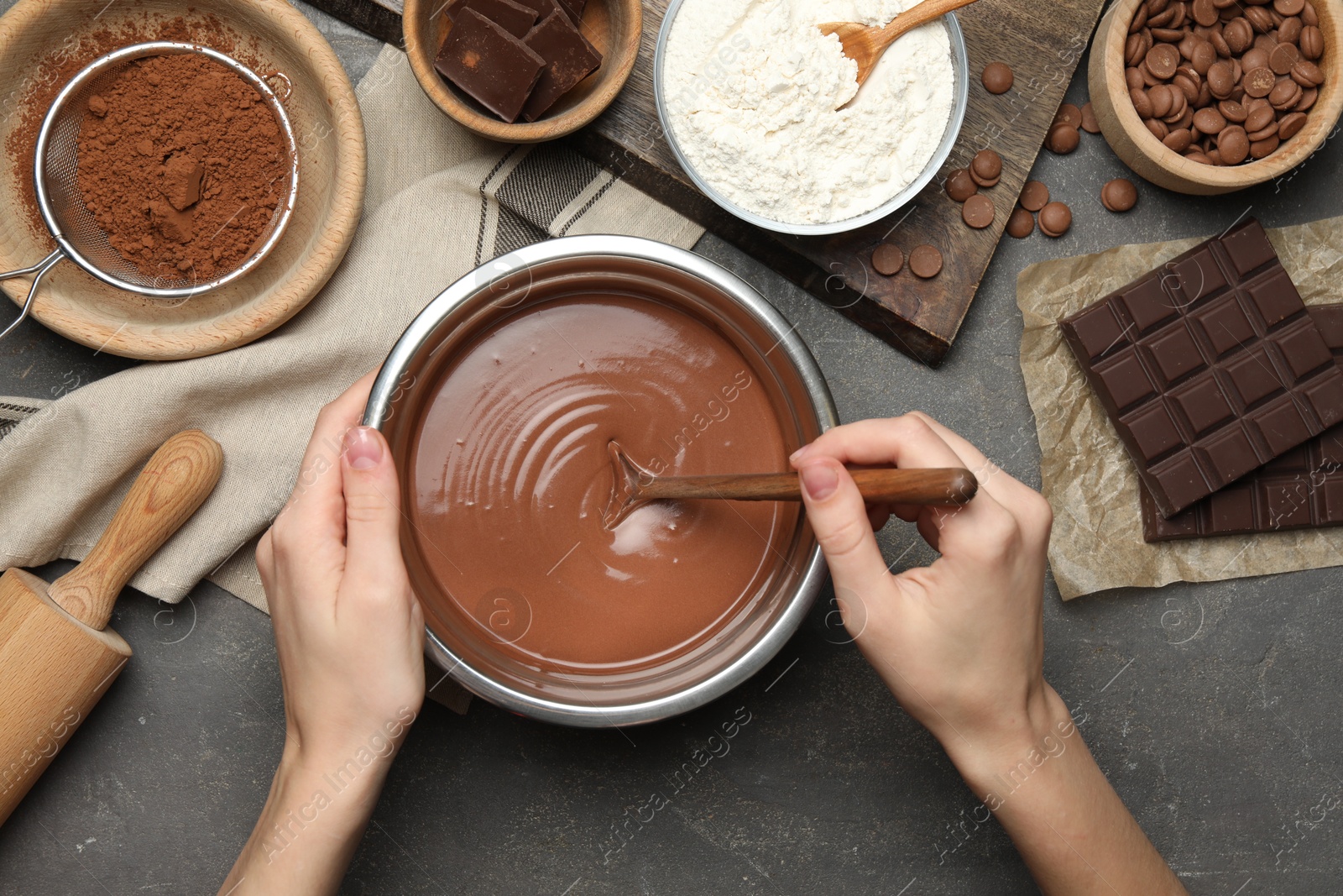 Photo of Woman making chocolate dough at grey table, top view