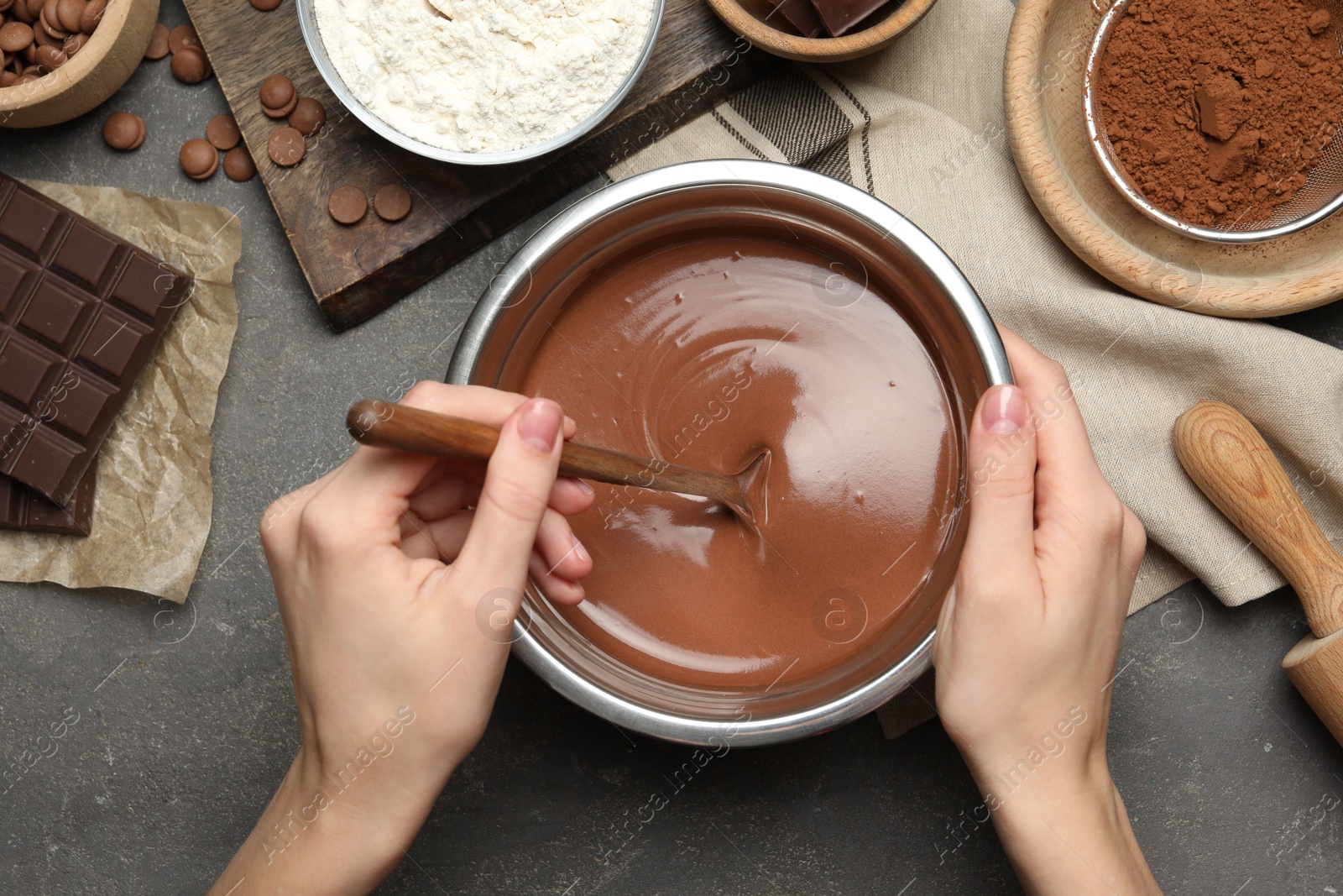 Photo of Woman making chocolate dough at grey table, top view