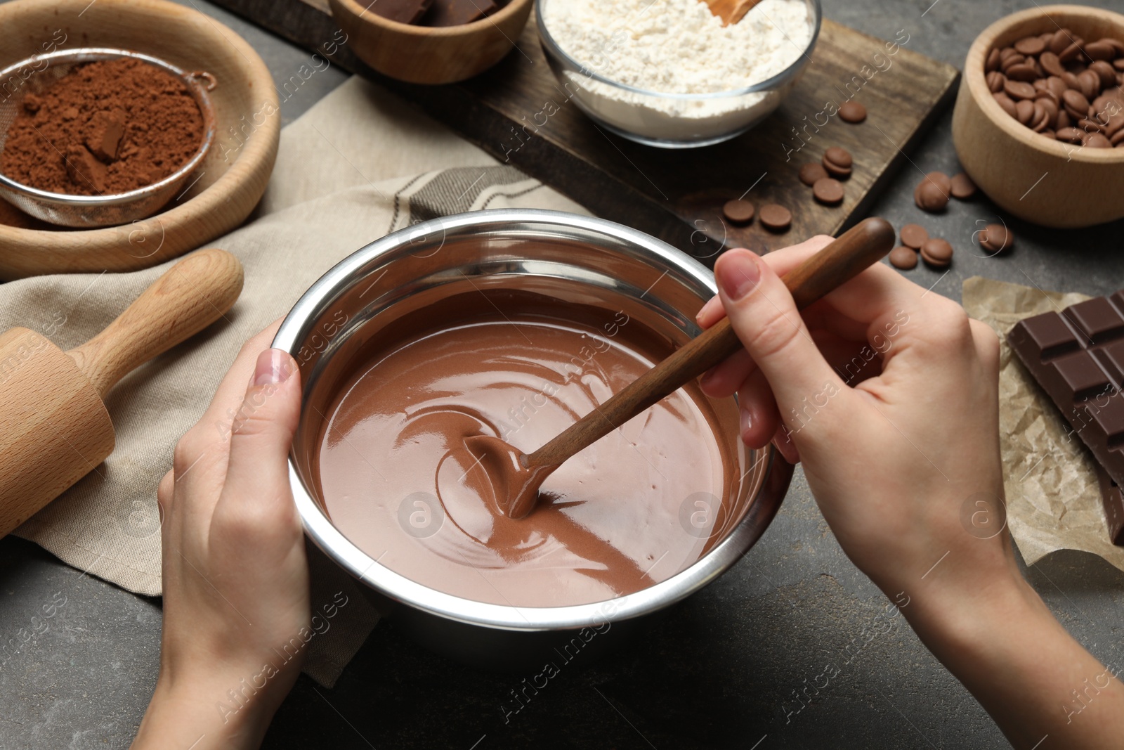 Photo of Woman making chocolate dough at grey table, closeup