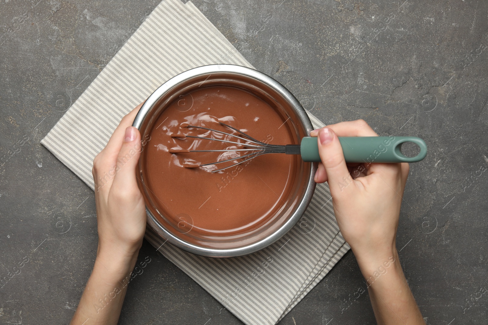 Photo of Woman mixing chocolate dough with whisk at grey table, top view