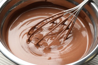 Photo of Chocolate dough and whisk in bowl on table, closeup