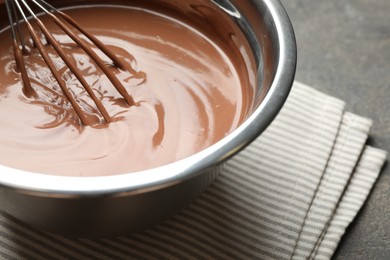 Photo of Chocolate dough and whisk in bowl on grey table, closeup