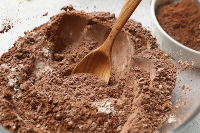 Photo of Making chocolate dough. Mix of cocoa powder with flour and spoon in bowl, closeup