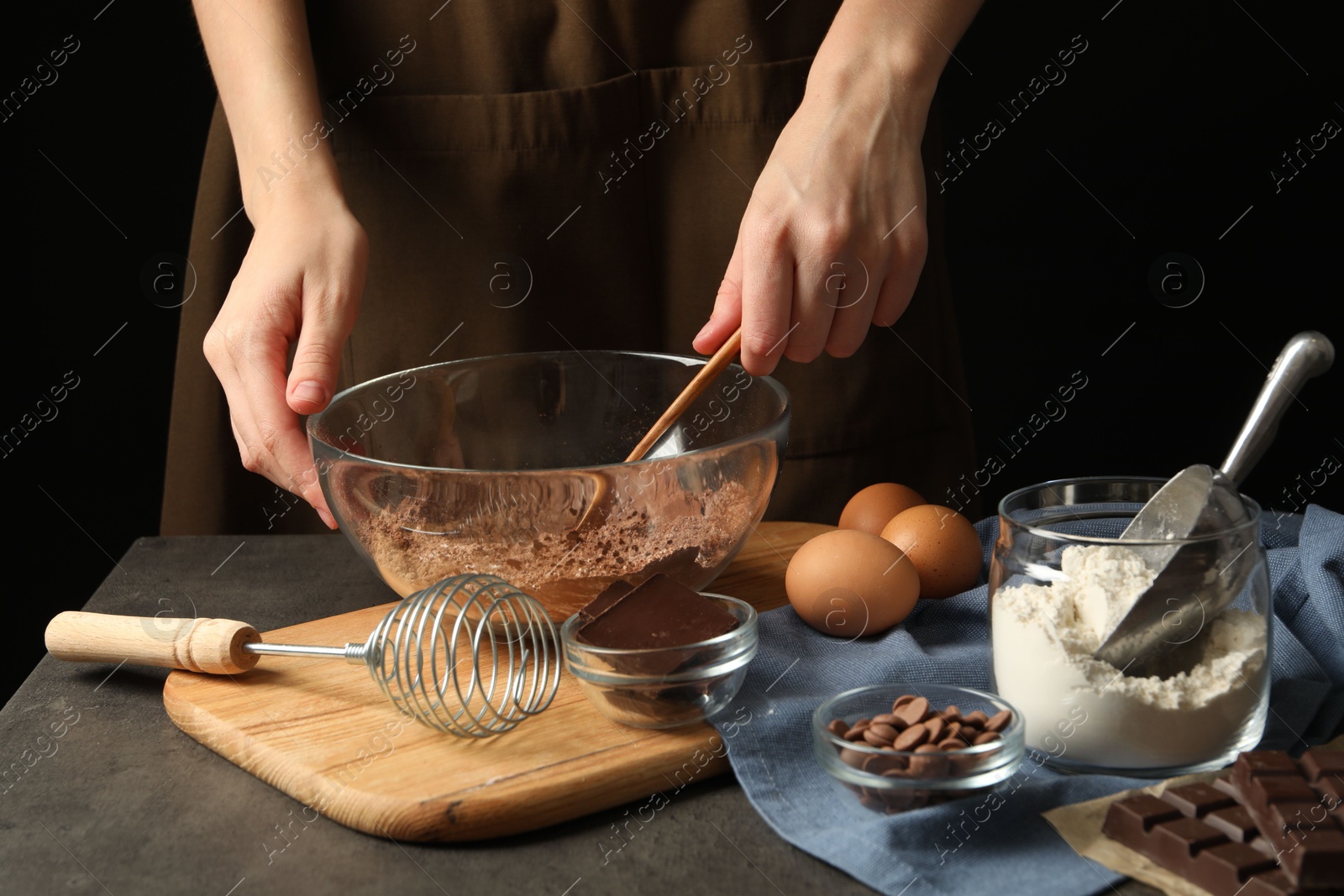 Photo of Woman making chocolate dough at grey table, closeup