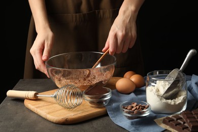 Photo of Woman making chocolate dough at grey table, closeup