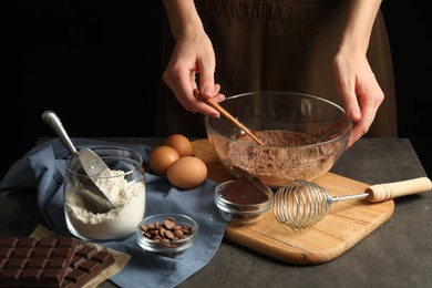 Photo of Woman making chocolate dough at grey table, closeup