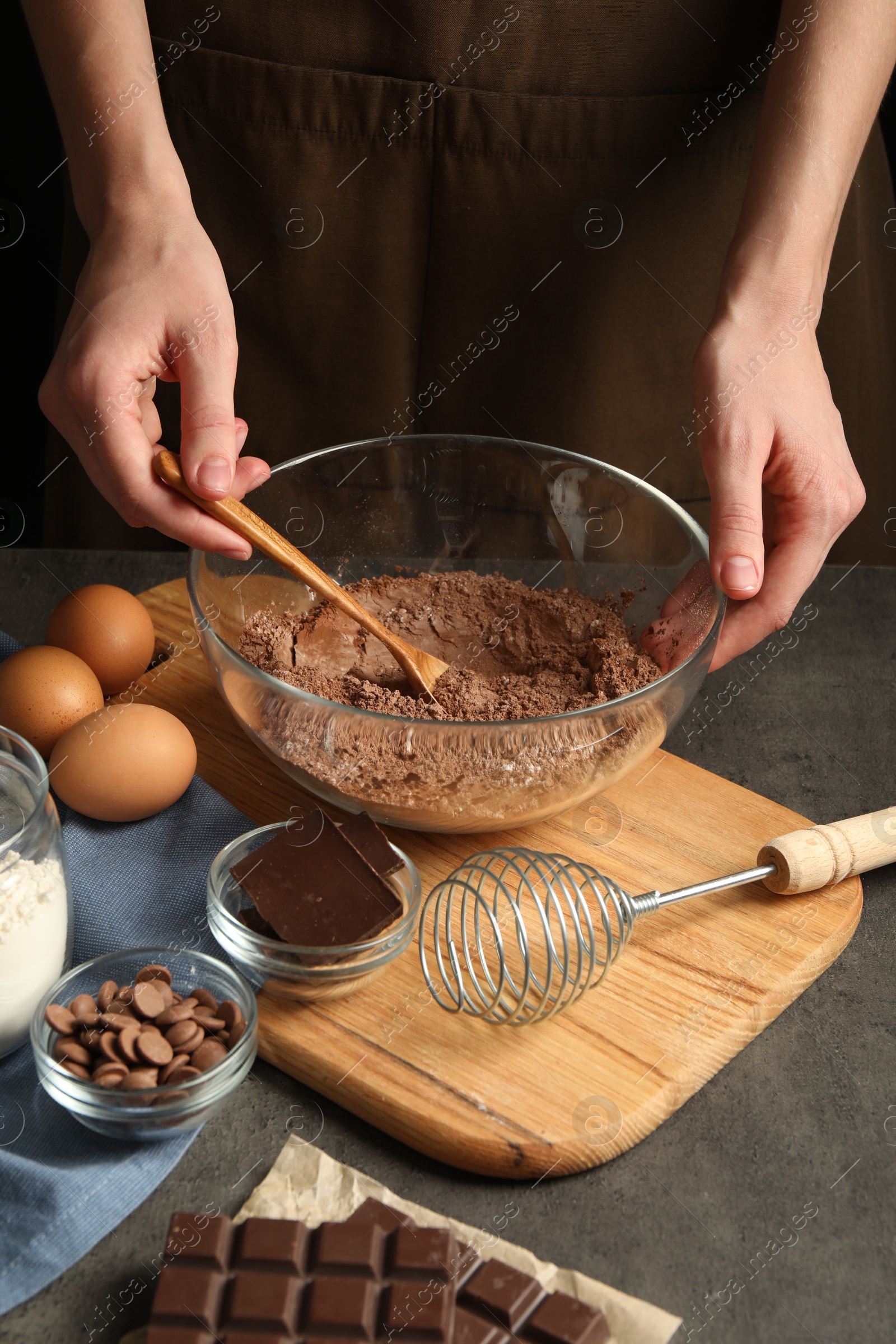 Photo of Woman making chocolate dough at grey table, closeup