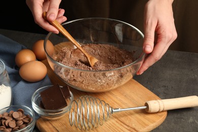 Photo of Woman making chocolate dough at grey table, closeup