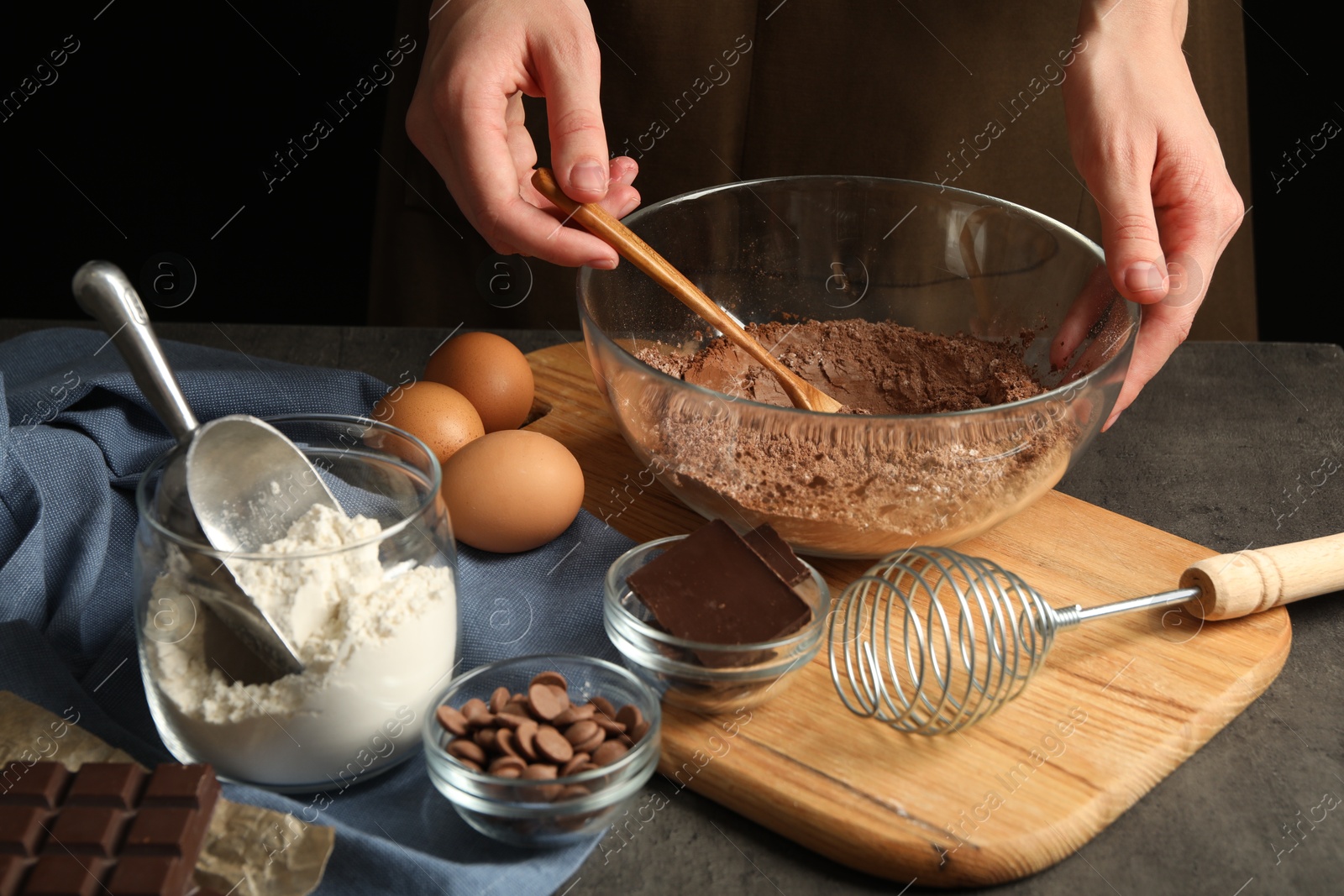 Photo of Woman making chocolate dough at grey table, closeup