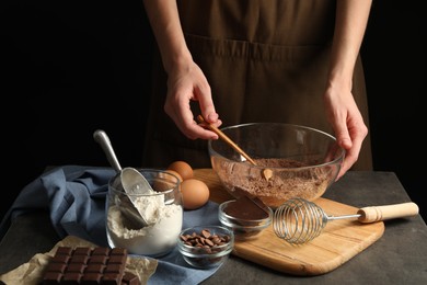 Photo of Woman making chocolate dough at grey table, closeup