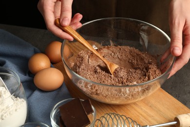 Photo of Woman making chocolate dough at grey table, closeup