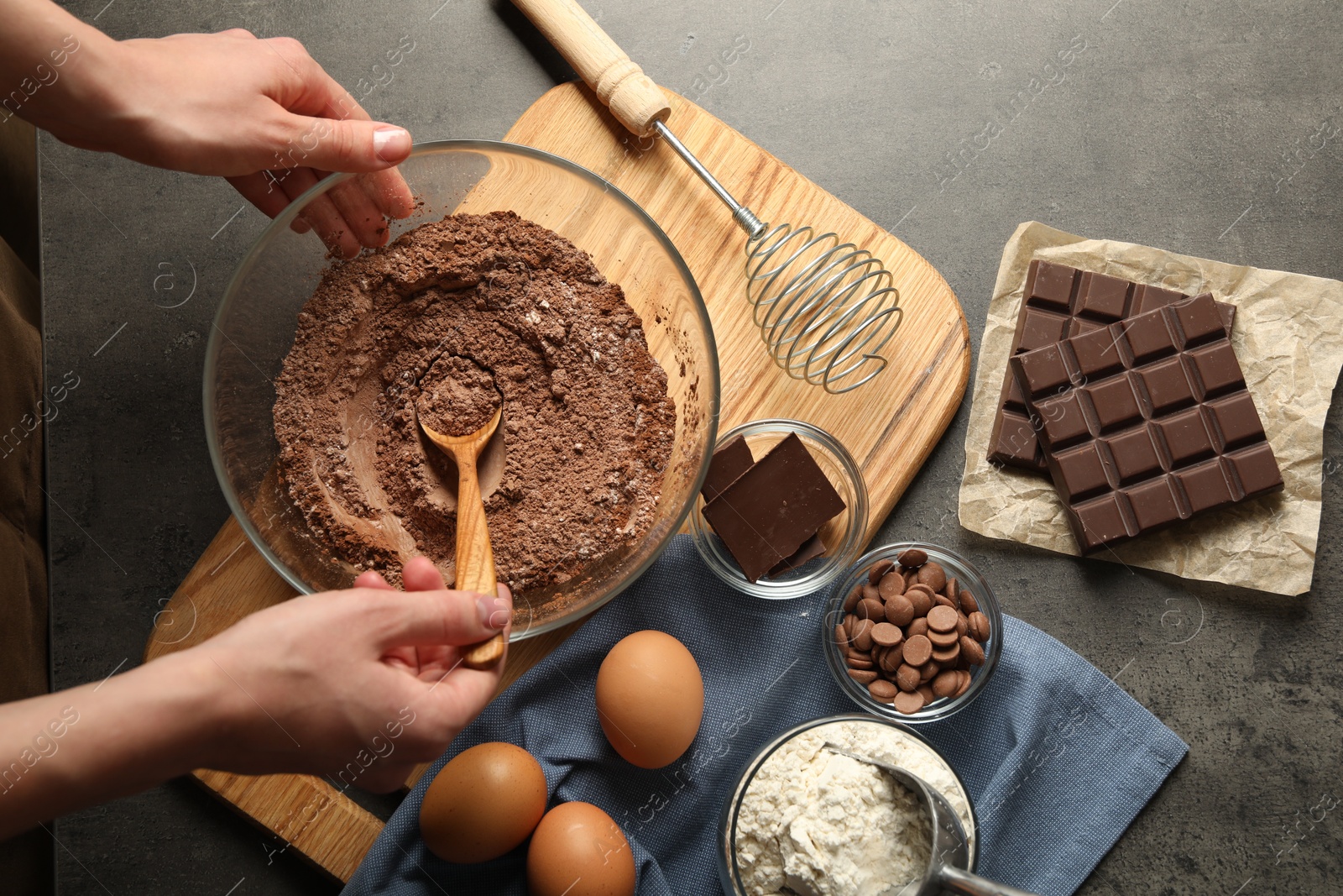 Photo of Woman making chocolate dough at grey table, top view