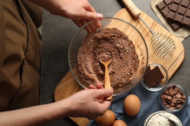 Photo of Woman making chocolate dough at grey table, top view