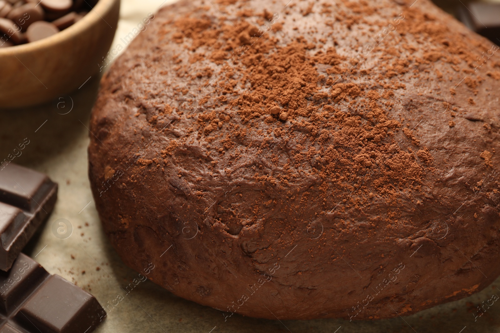 Photo of Chocolate dough and ingredients on parchment, closeup