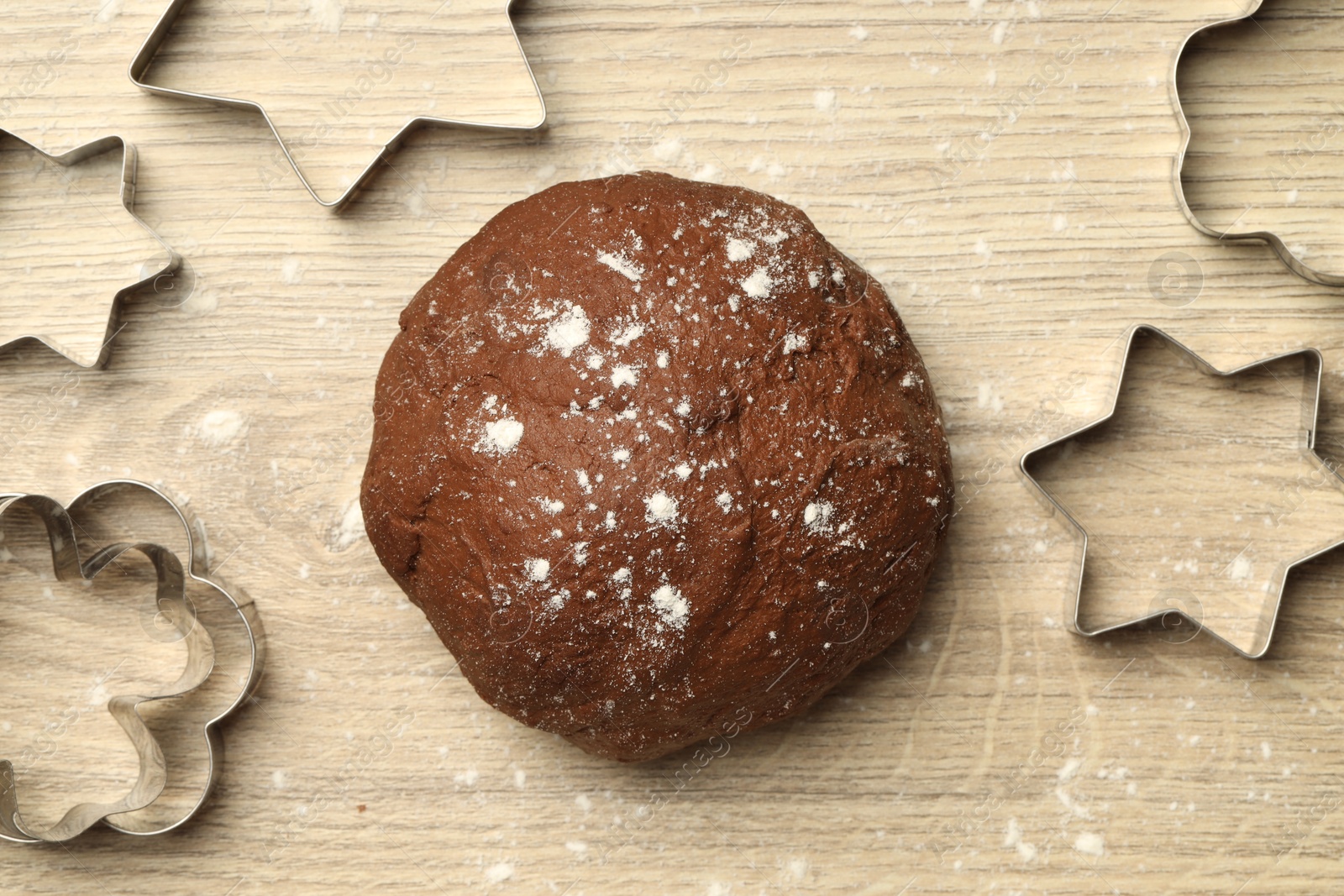 Photo of Chocolate dough and cookie cutters on wooden table, flat lay