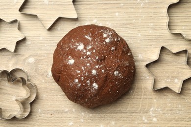 Photo of Chocolate dough and cookie cutters on wooden table, flat lay