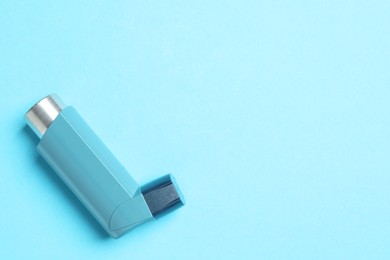 Photo of Asthma inhaler on light blue background, top view. Space for text