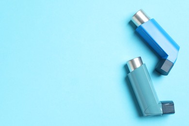 Photo of Asthma inhalers on light blue background, flat lay. Space for text