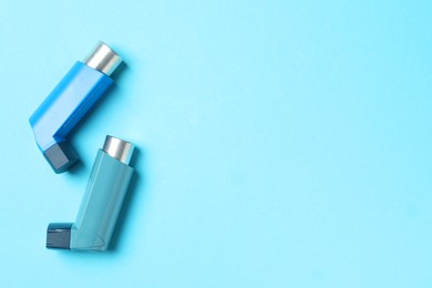 Photo of Asthma inhalers on light blue background, flat lay. Space for text