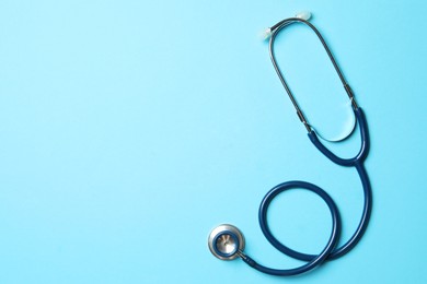 Photo of Stethoscope on light blue background, top view. Space for text