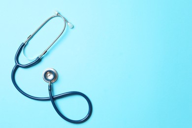 Photo of Stethoscope on light blue background, top view. Space for text