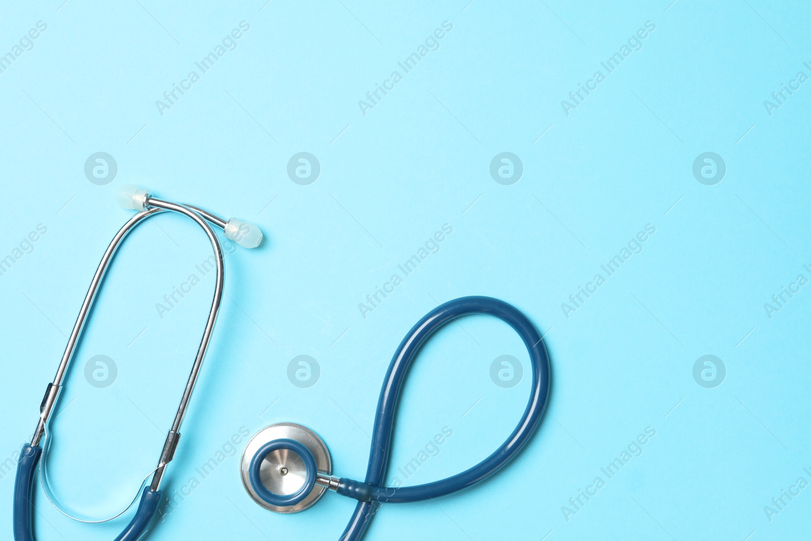 Photo of Stethoscope on light blue background, top view. Space for text