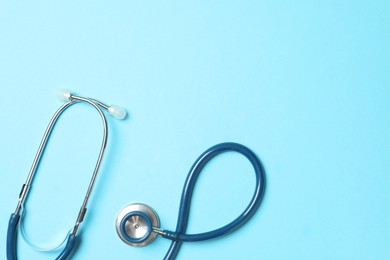 Photo of Stethoscope on light blue background, top view. Space for text