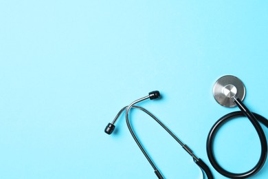 Photo of Stethoscope on light blue background, top view. Space for text