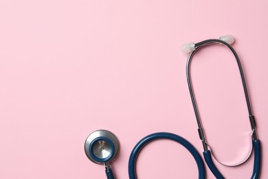 Photo of Stethoscope on pink background, top view. Space for text