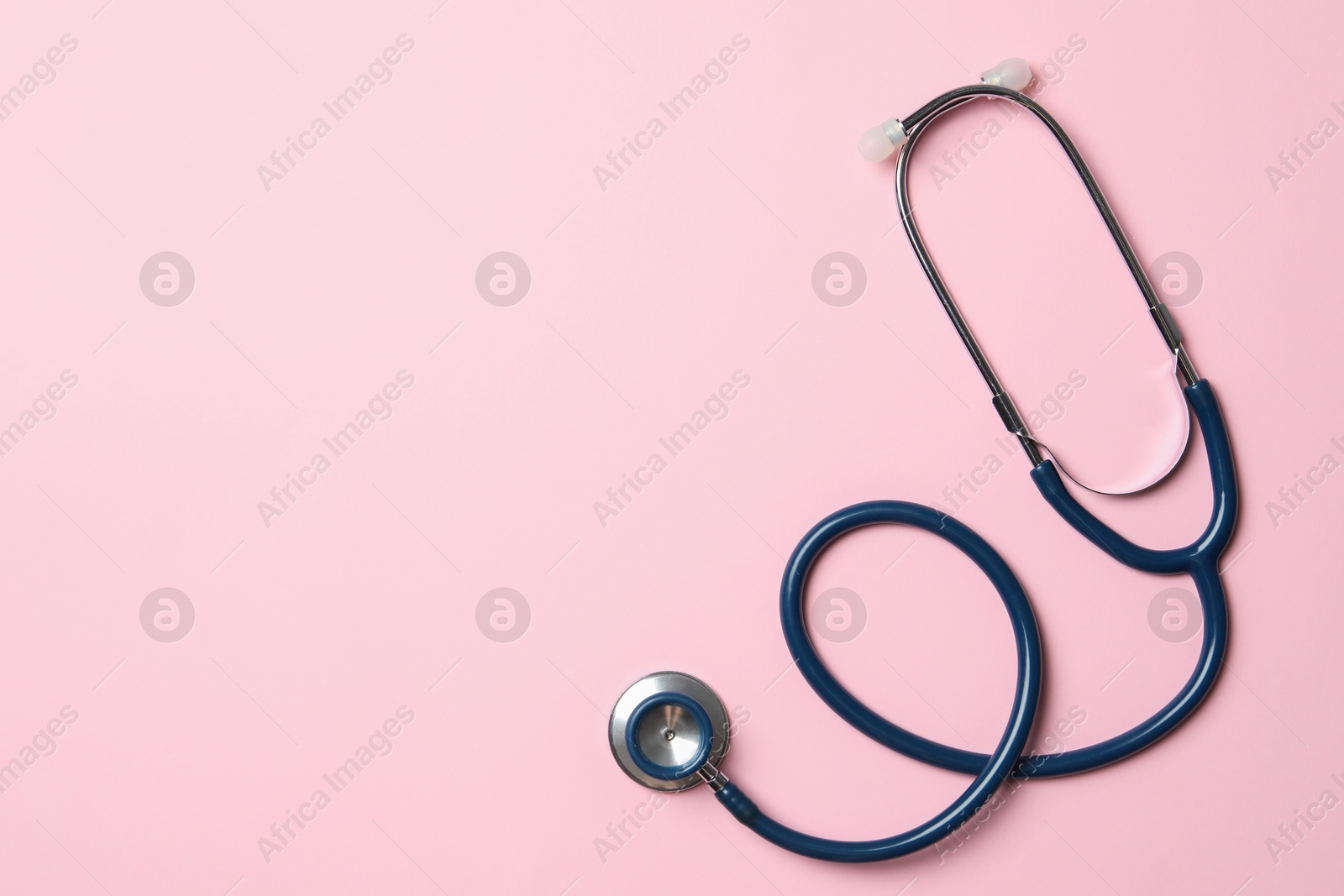 Photo of Stethoscope on pink background, top view. Space for text