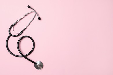 Photo of Stethoscope on pink background, top view. Space for text