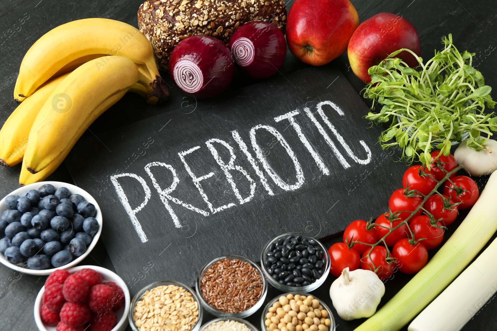 Photo of Slate board with word Prebiotic and different fresh products on black table