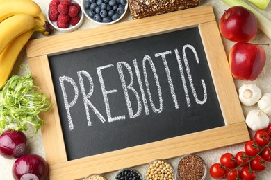 Photo of Chalkboard with word Prebiotic and different fresh products on grey table, flat lay