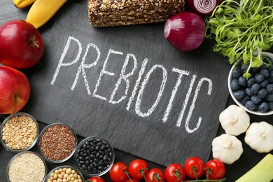 Photo of Slate board with word Prebiotic and different fresh products on black table, flat lay