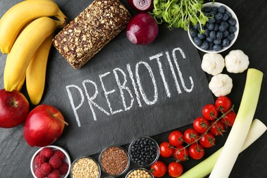 Photo of Slate board with word Prebiotic and different fresh products on black table, flat lay