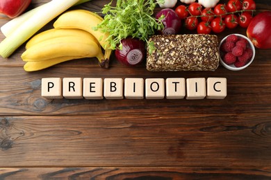 Photo of Wooden cubes with word Prebiotic and different fresh products on table, flat lay. Space for text