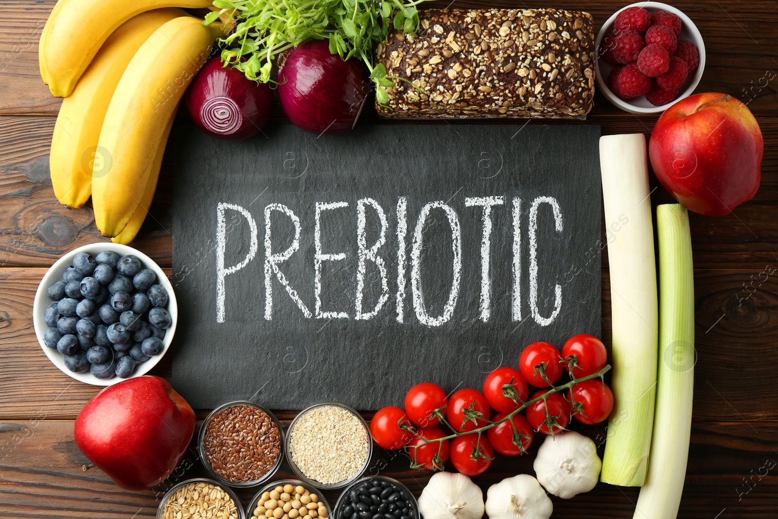 Photo of Slate board with word Prebiotic and different fresh products on wooden table, flat lay