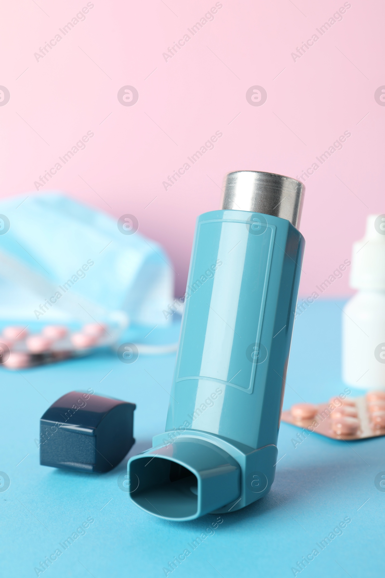 Photo of Asthma inhaler and other medications on color background, closeup