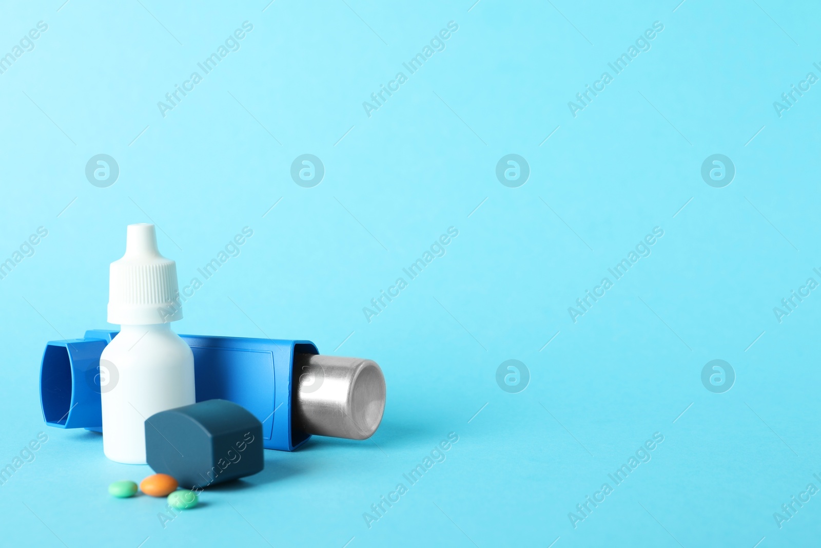 Photo of Different asthma medications on light blue background, closeup. Space for text