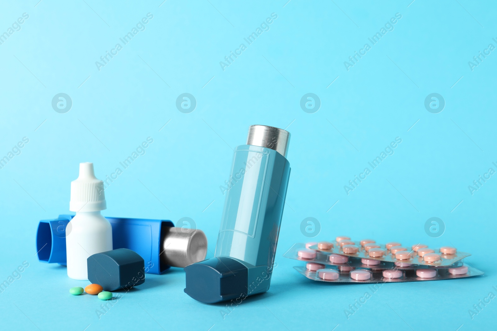 Photo of Different asthma medications on light blue background, closeup