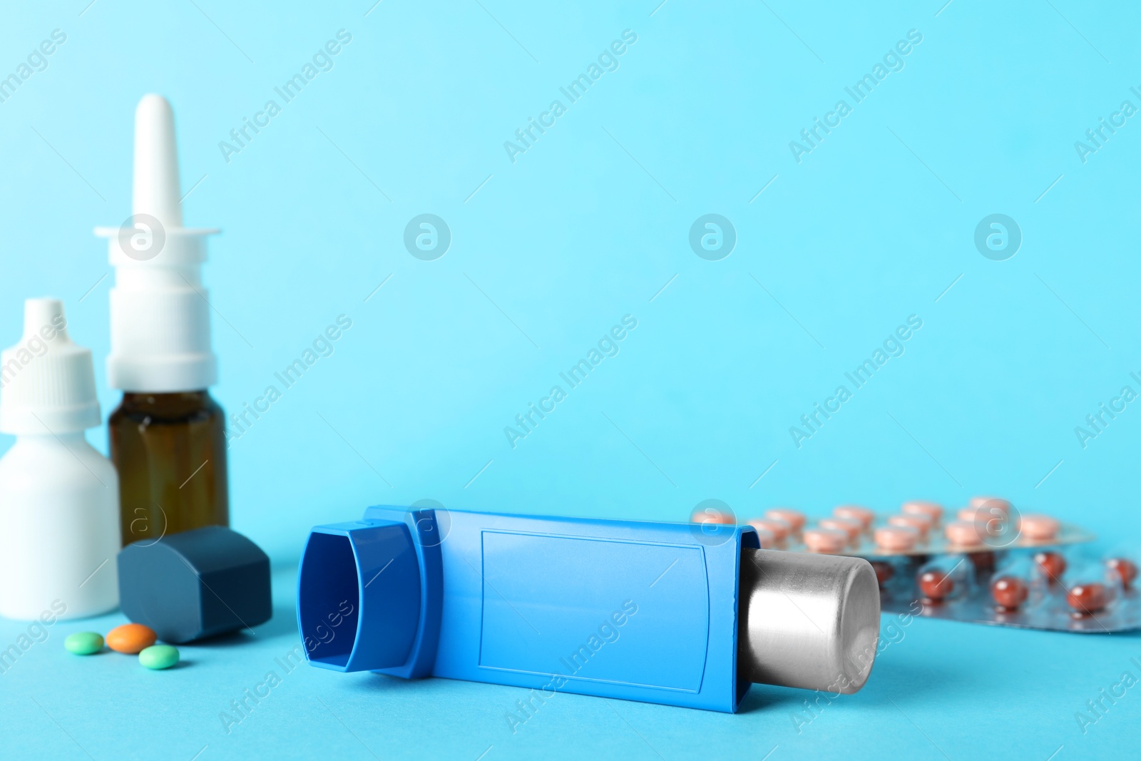 Photo of Different asthma medications on light blue background, closeup